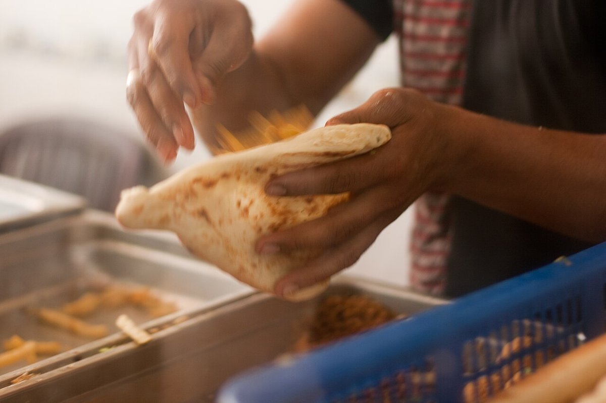 An Iraqi falafel sandwich being assembled in samoon bread