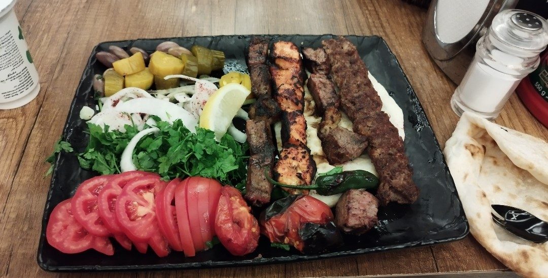 An Iraqi mixed grill platter with kebab, tikka, salad and bread, a typical restaurant meal