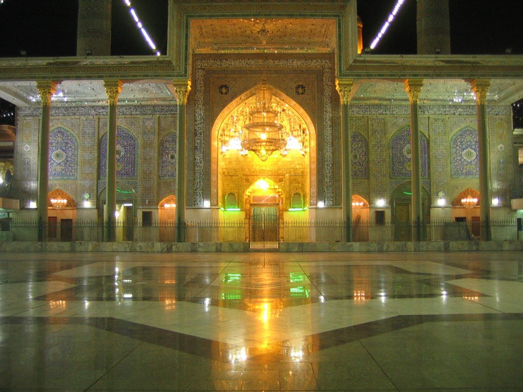 The tiled courtyard and golden portal of the Kadhimiya shrine in Baghdad at night