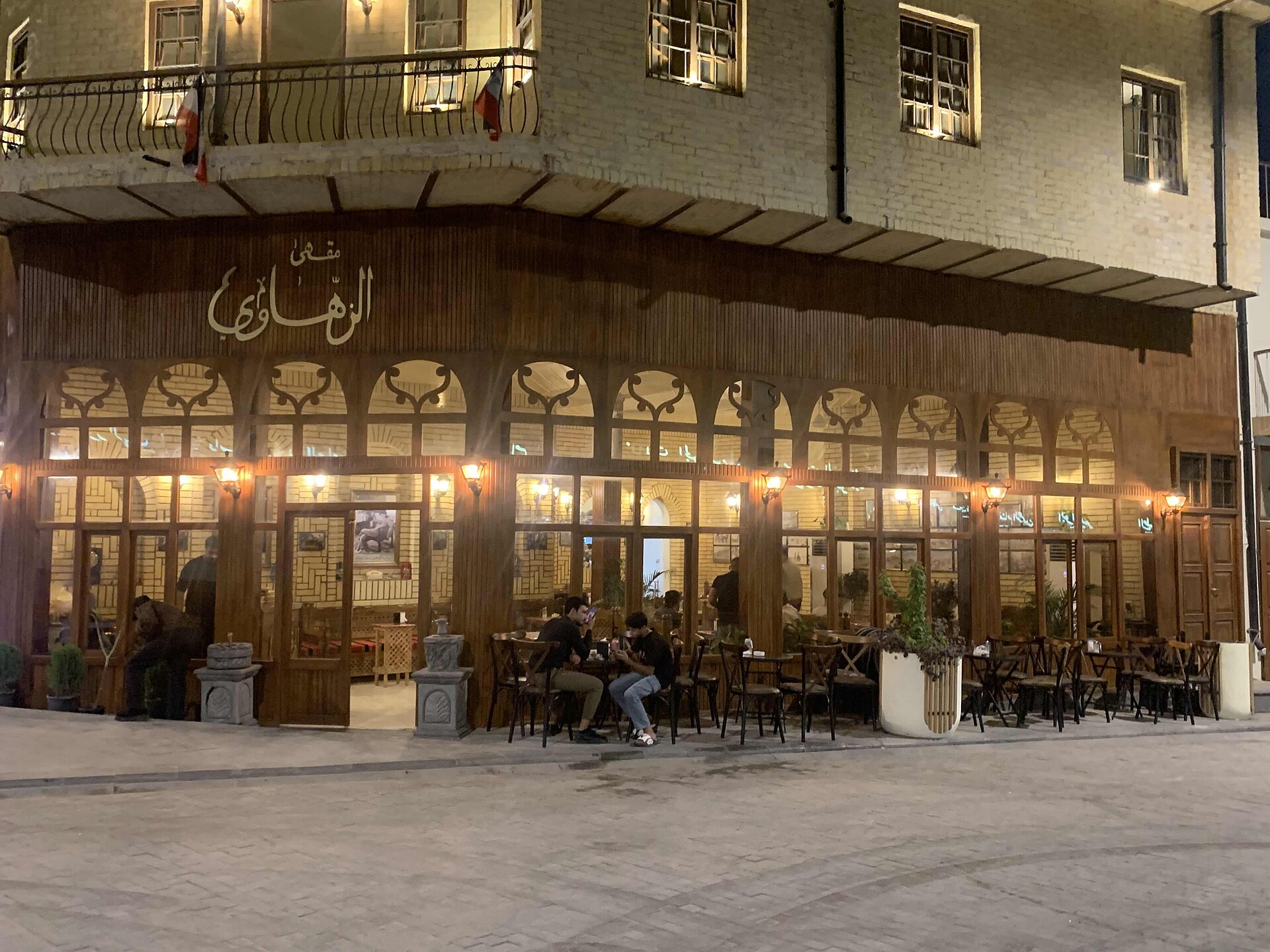 Restored heritage coffeehouse on Rasheed Street in Baghdad lit up at night with customers at outdoor tables