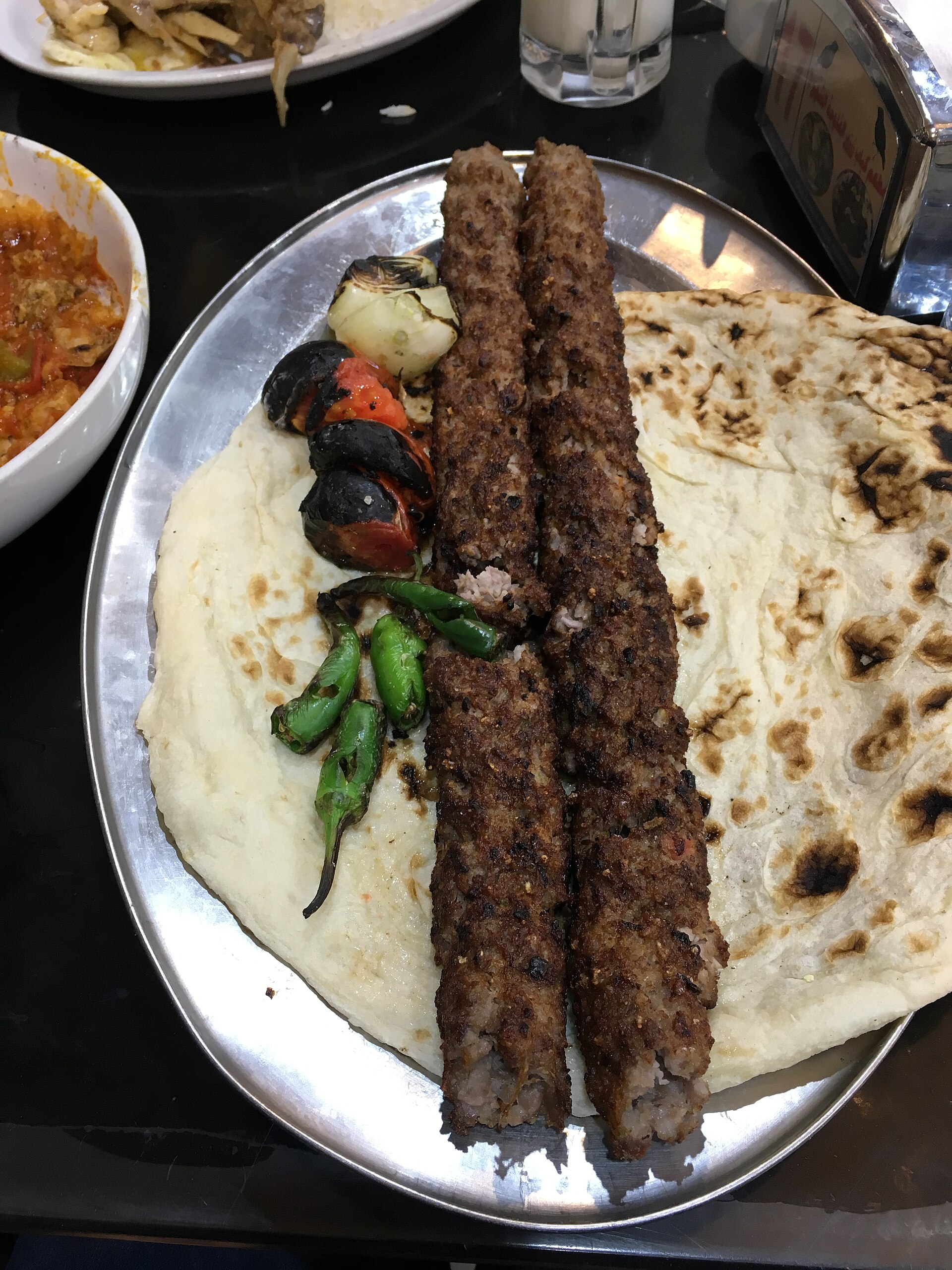 Iraqi kebab served on flat skewers with grilled vegetables and flatbread at a restaurant in Baghdad