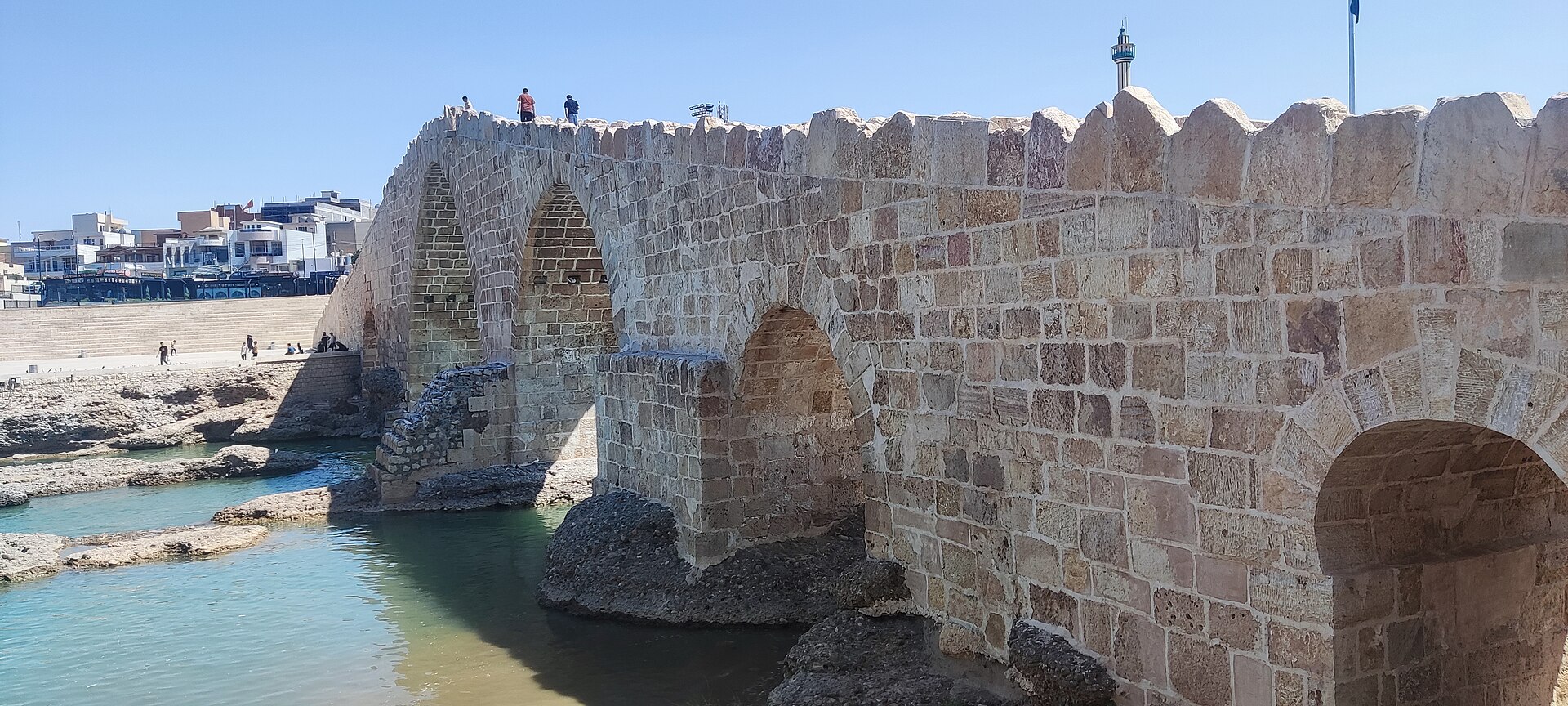The pointed stone arches and crenellated parapet of the Delal Bridge over the Khabur river at Zakho
