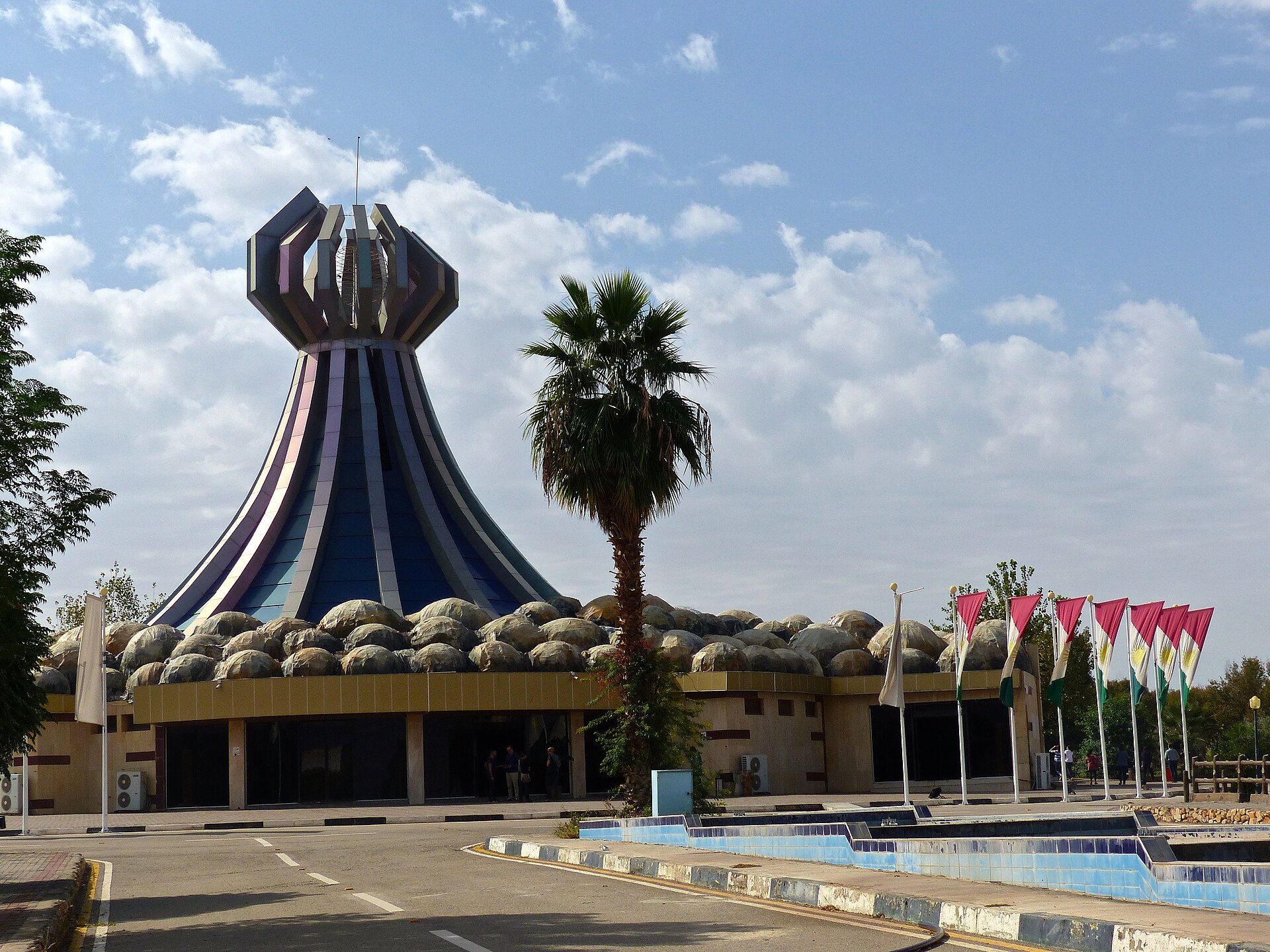 The Halabja Monument and Peace Museum, a dark flared tower flanked by Kurdish flags at the entrance to Halabja