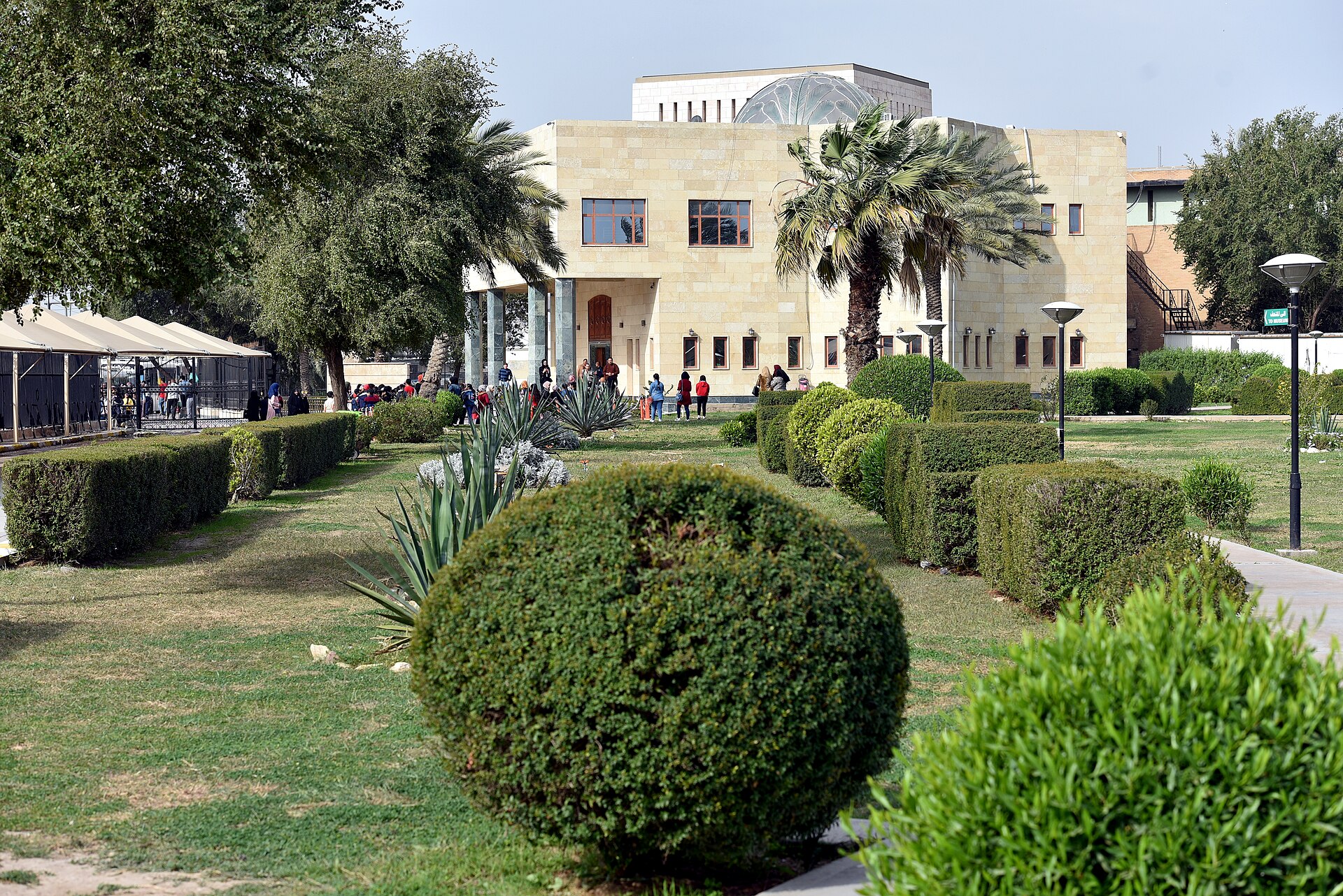 Visitors walking through the gardens and courtyard of the Iraq Museum compound in Baghdad