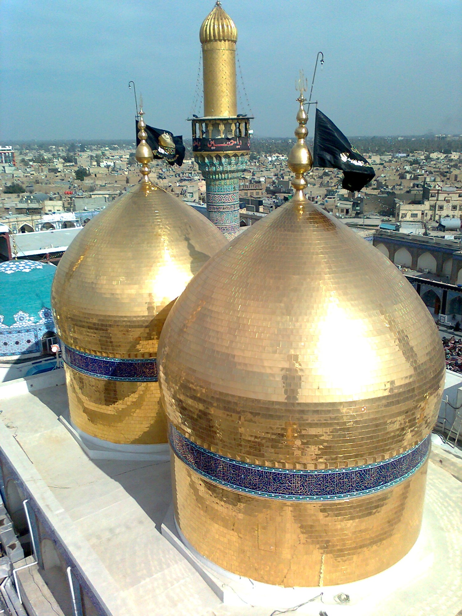 The two equally sized gold domes of the Kadhimiya shrine seen from roof level above the district