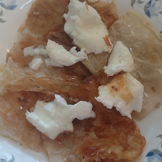 Iraqi kahi pastry topped with thick white geymar clotted cream on a plate