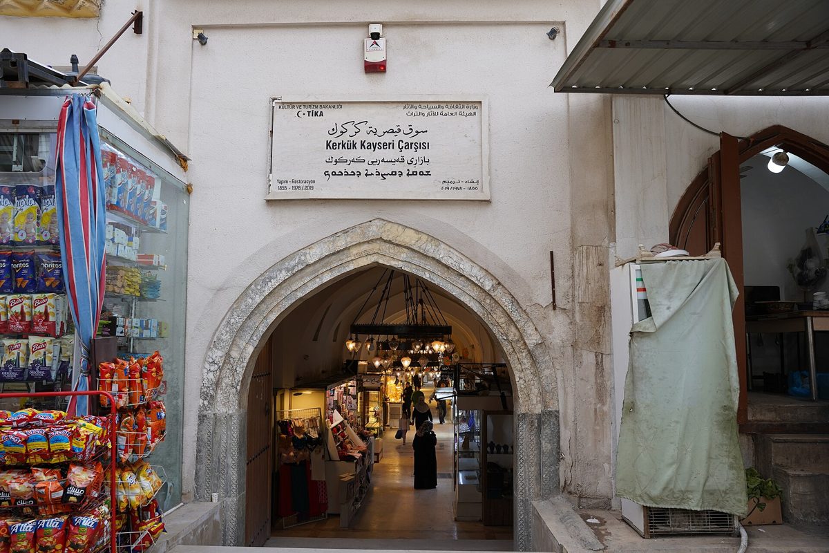 Arched entrance to the historic Qaysariyya bazaar in Kirkuk with trilingual sign