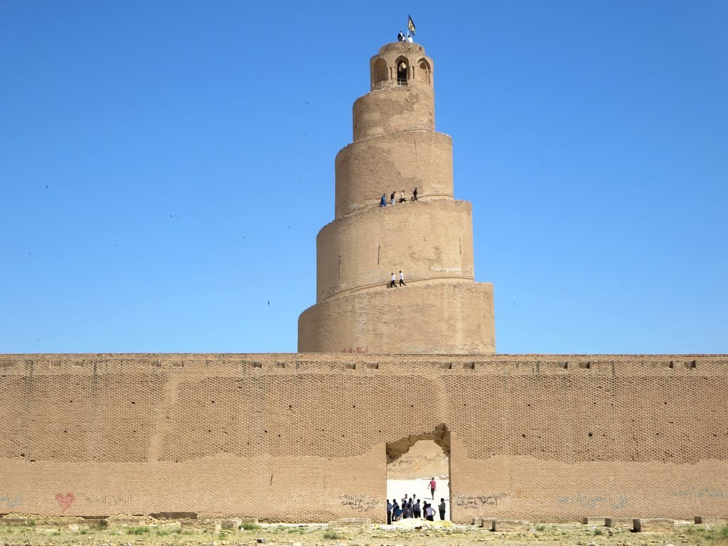 The spiral Malwiya minaret of the Great Mosque of Samarra rising behind the mosque outer wall