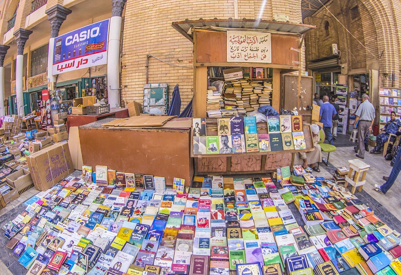 Second-hand books laid out on the ground beneath a brick arcade on Mutanabbi Street in Baghdad