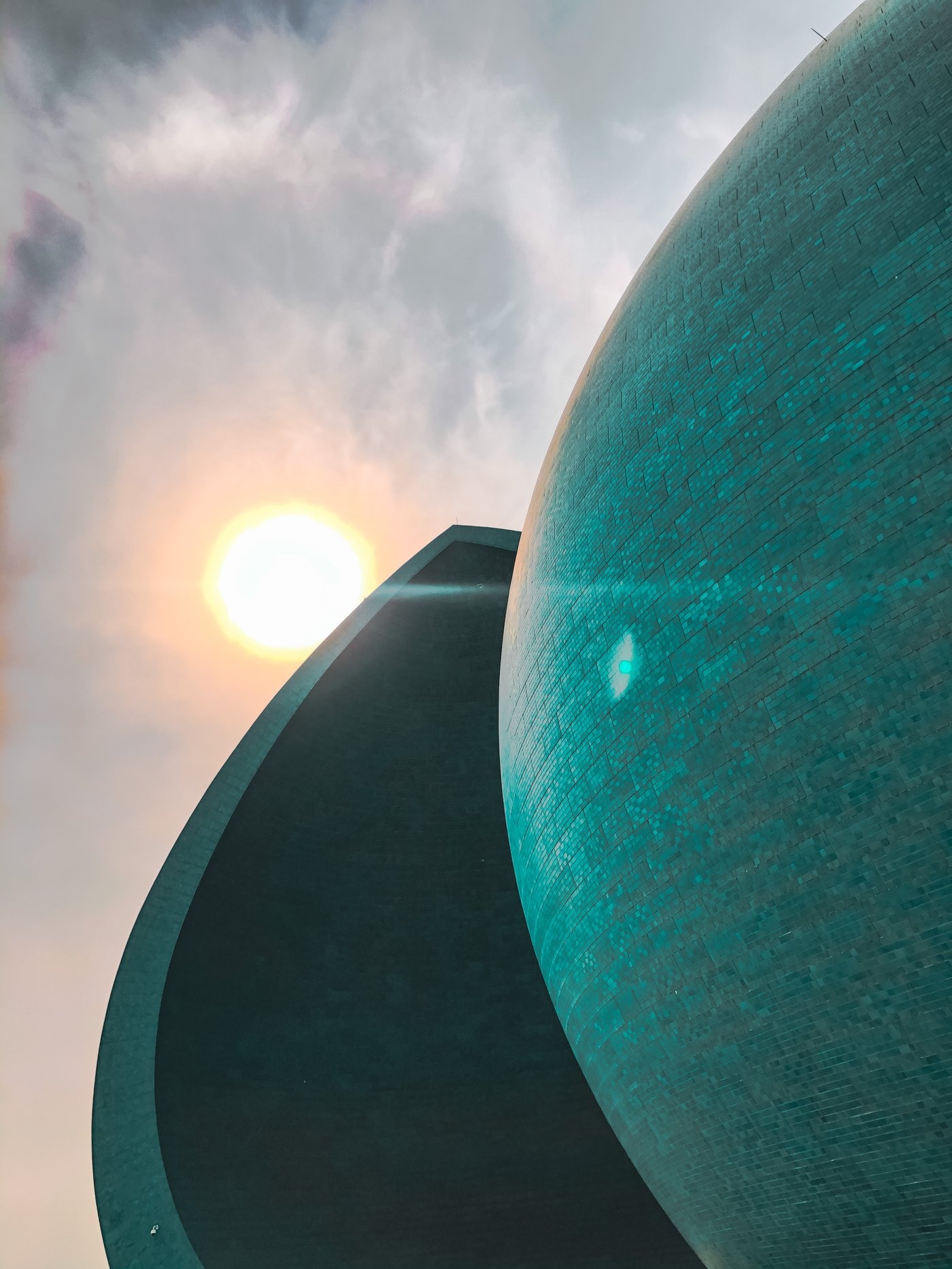 Close view of the glazed turquoise ceramic tiles on one half of the Al-Shaheed Monument dome at sunset