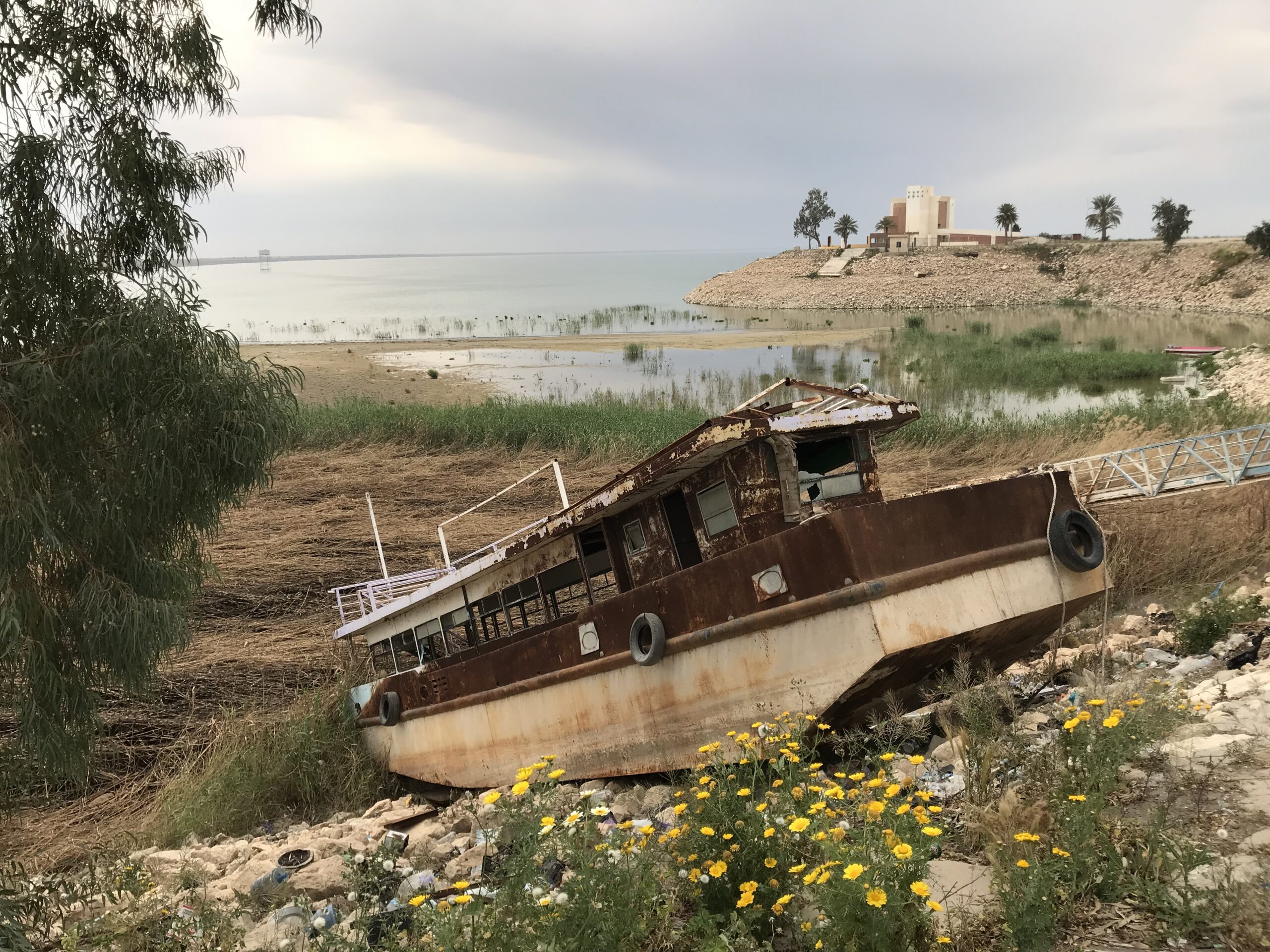 A rusting passenger boat beached on dry ground beside the shrunken shoreline of Lake Habbaniyah