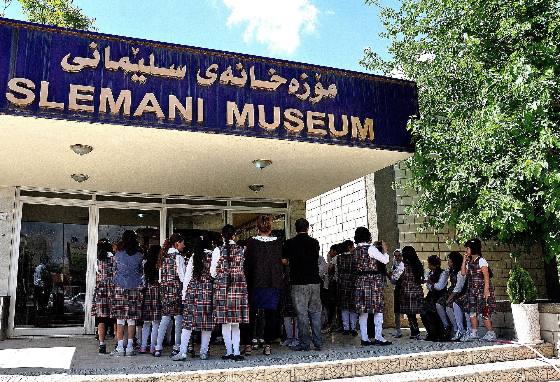 School groups at the entrance to the Slemani Museum in Sulaymaniyah, under its bilingual Kurdish and English sign