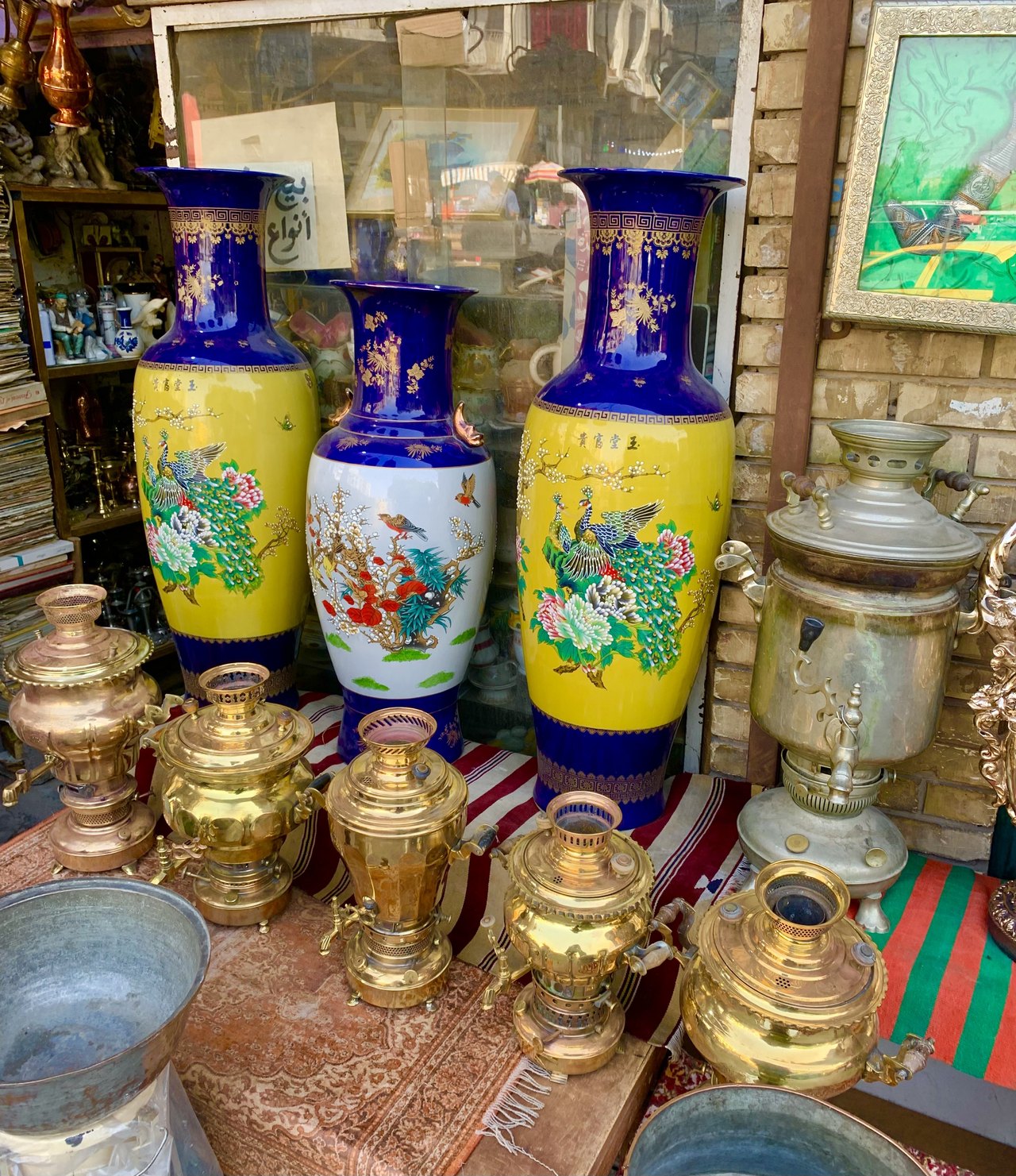 Brass samovars, oil lamps and painted vases displayed on a rug at Souk al-Haraj, a second-hand market in Baghdad