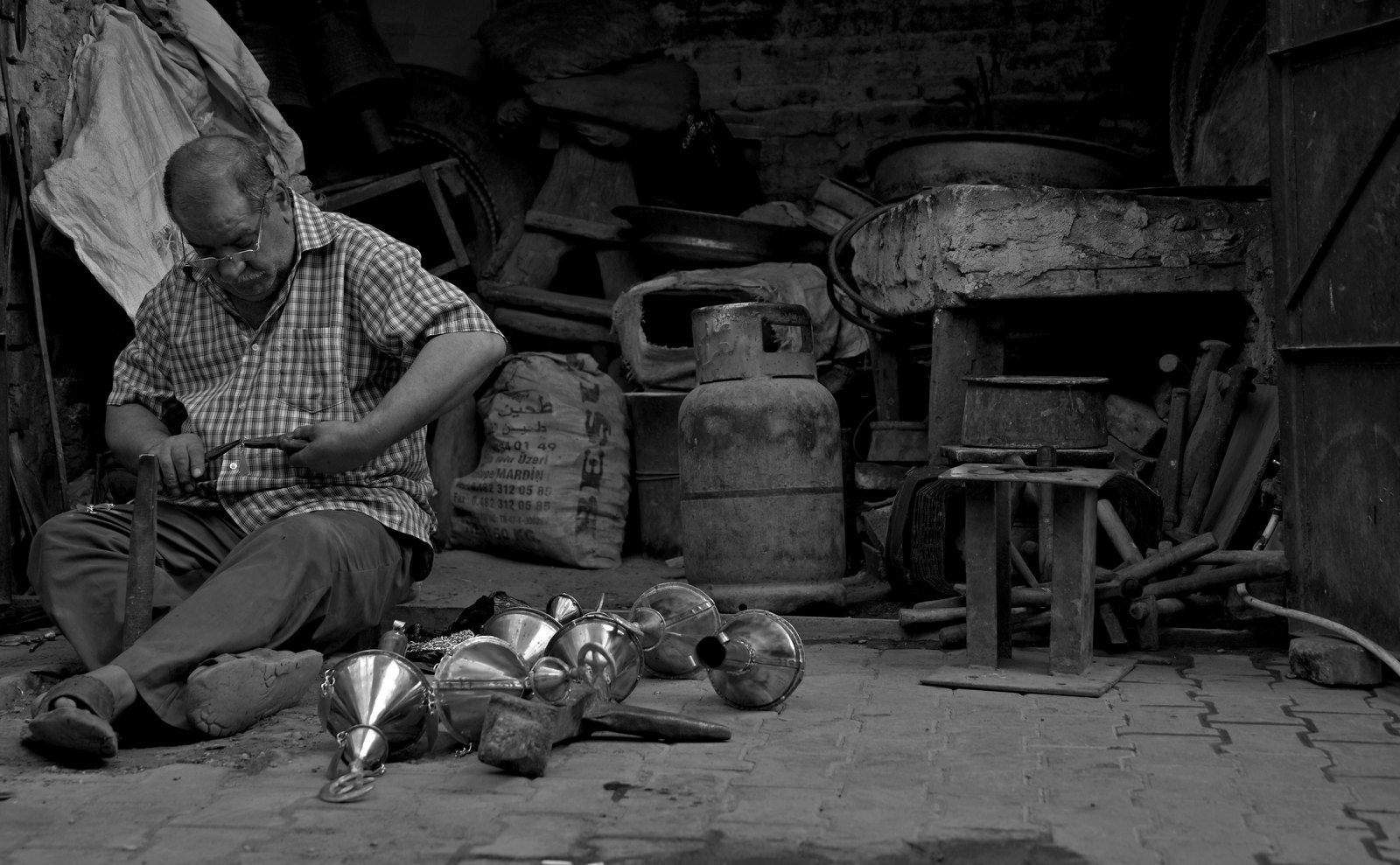 A coppersmith working by hand among finished vessels in Souk al-Safafeer, old Baghdad