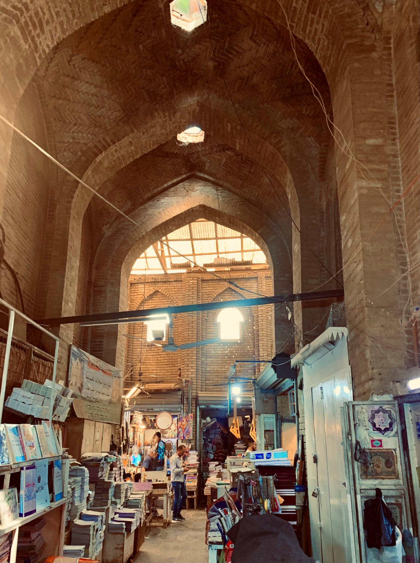 Stacks of books and stationery under the tall brick vaults of Souk al-Saray in Baghdad