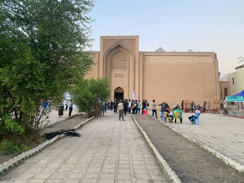 Visitors in front of the brick facade and patterned walls of the Abbasid Palace in Baghdad, a stop on this Baghdad itinerary