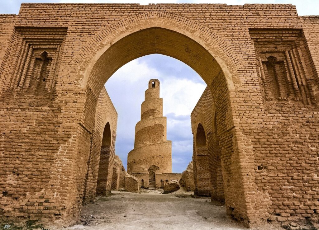 The smaller spiral minaret of the Abu Dulaf Mosque at Samarra, framed by a tall brick arch