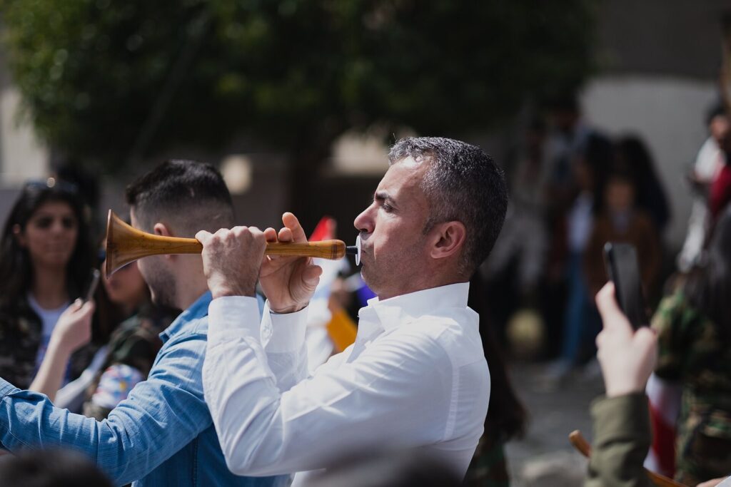 A man playing a horn in the Akitu parade for the Assyrian New Year in Duhok, surrounded by the crowd