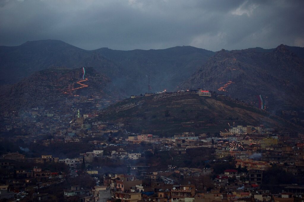 A zigzag trail of Newroz torches climbing the mountain above Akre at dusk