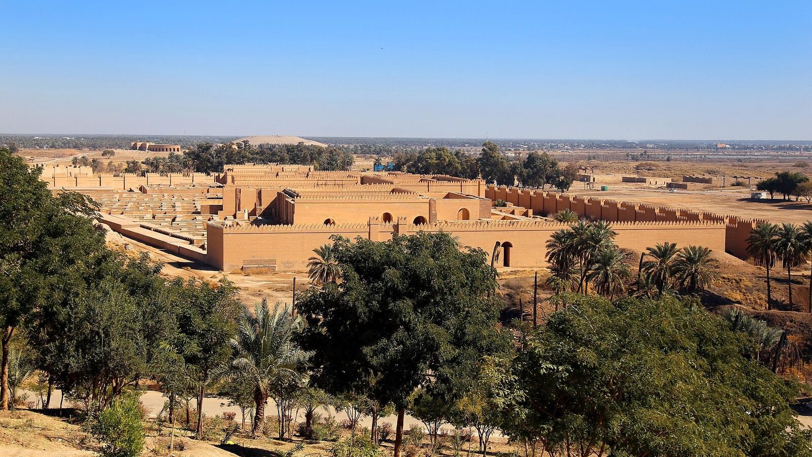 Overview of Babylon's reconstructed walls among palm groves near Hillah, Iraq