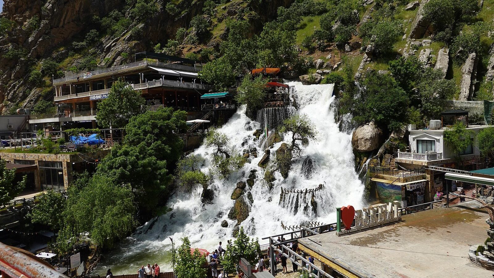 Bekhal waterfall pouring down a green gorge past terraces and restaurants near Rawanduz