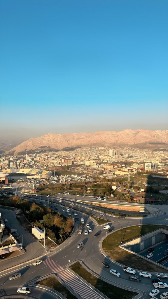 Duhok city spread along its valley below bare mountains at dusk