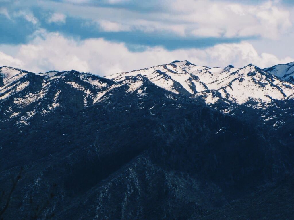 Snow-streaked mountain ridges near Duhok under a blue sky with white cloud