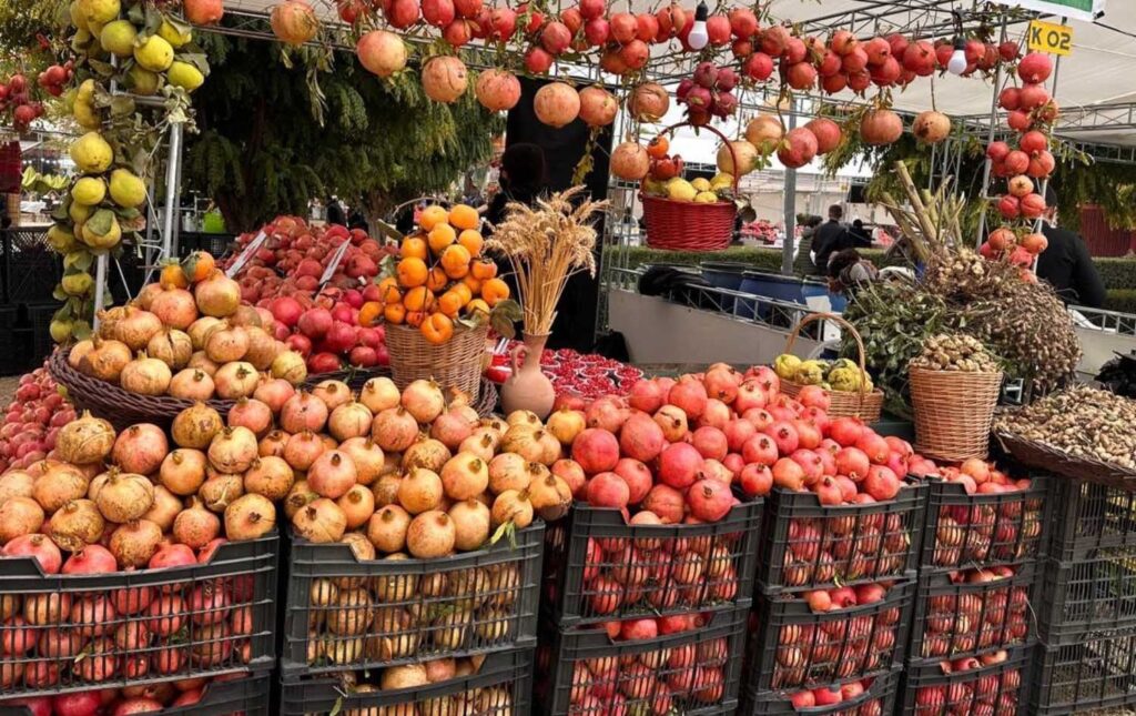Crates of pomegranates, apples and persimmons on a Halabja festival stall, a harvest scene from Iraq in October