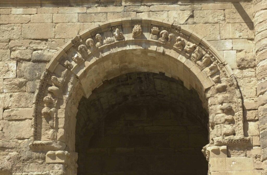 A stone arch at Hatra ringed with carved human heads and masks above a dark vaulted opening