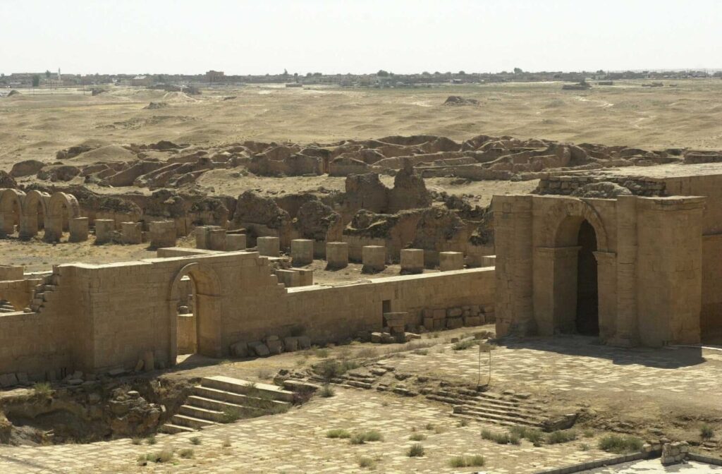 View across the ruins of Hatra, with arched temple walls and low stone foundations in the desert