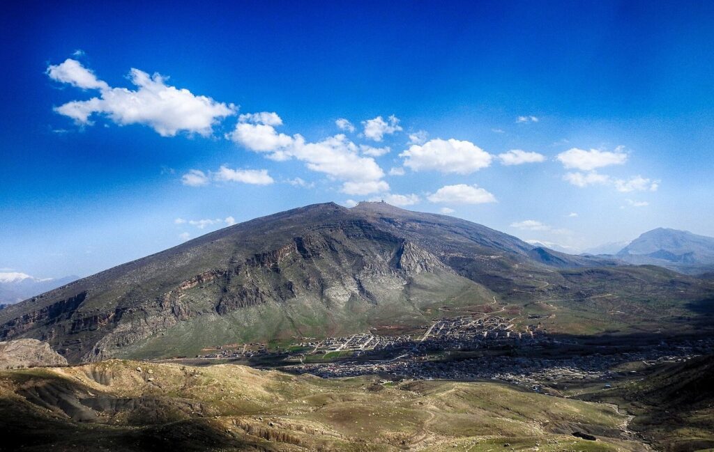 The bulk of Korek Mountain rising above the town of Khalifan under a blue sky