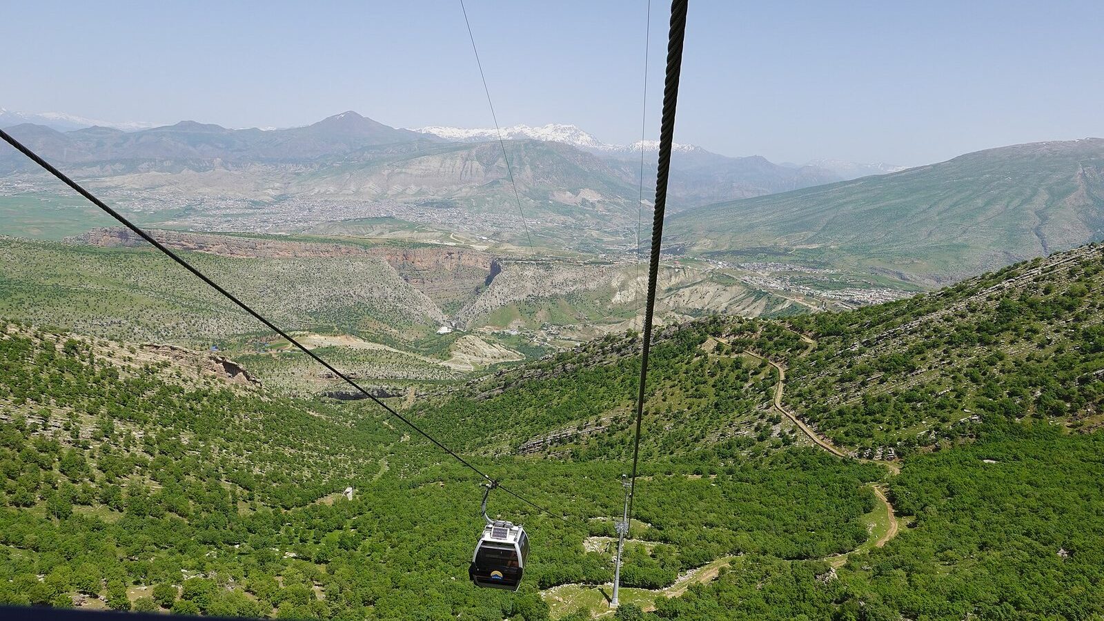 A Korek Mountain teleferic cabin descending over wooded slopes towards the valley