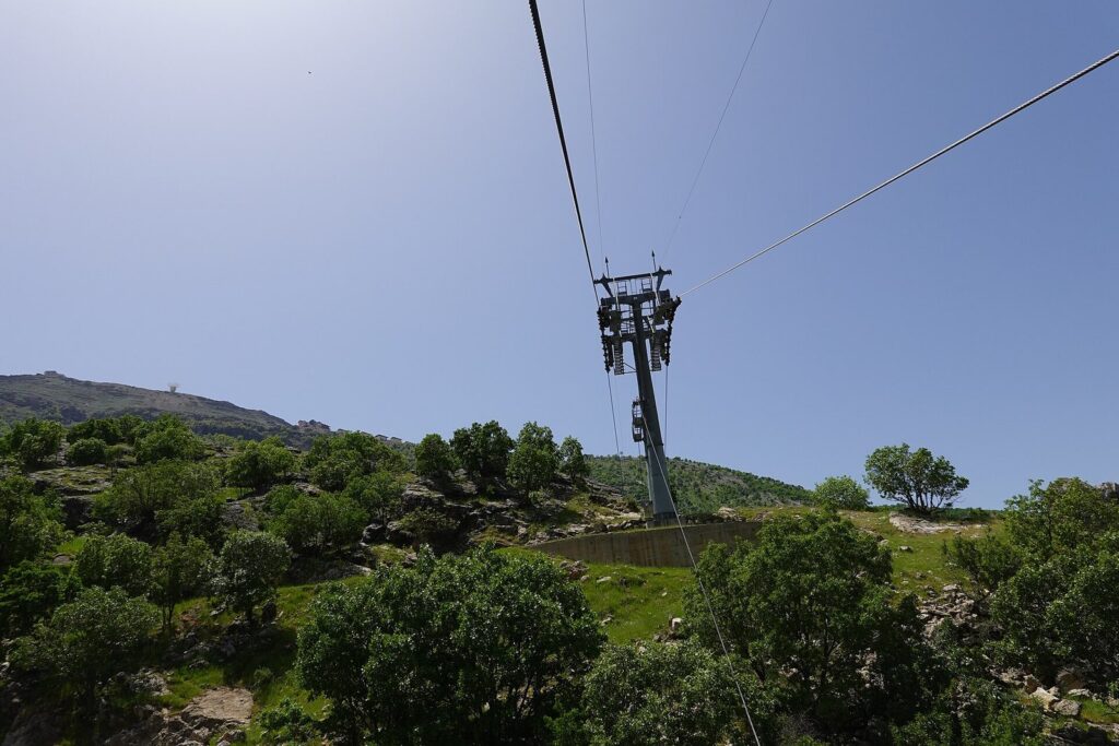 A Korek Mountain teleferic pylon and cables above wooded slopes