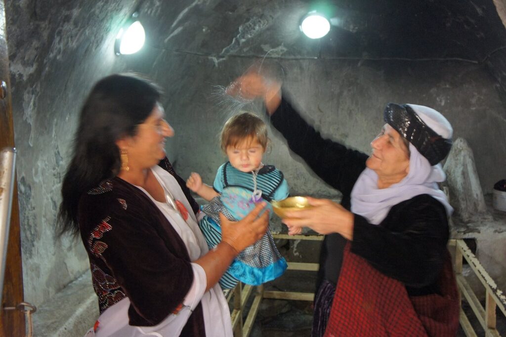 A Yazidi child being baptised with water from Kaniya Spi at Lalish