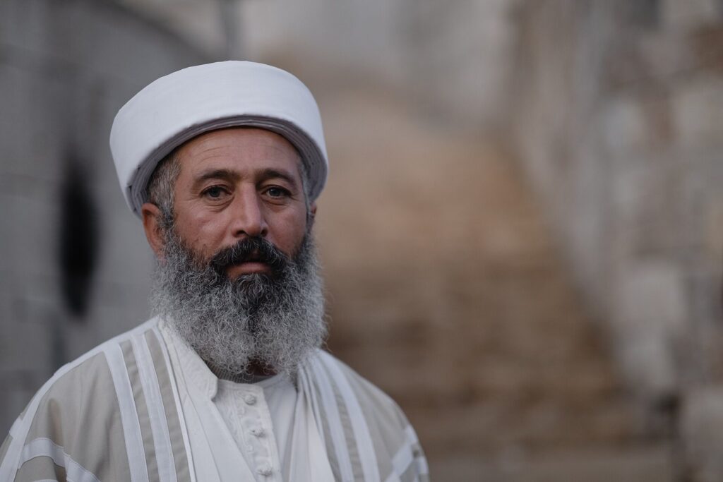 A Yazidi cleric in a white turban and robe at Lalish
