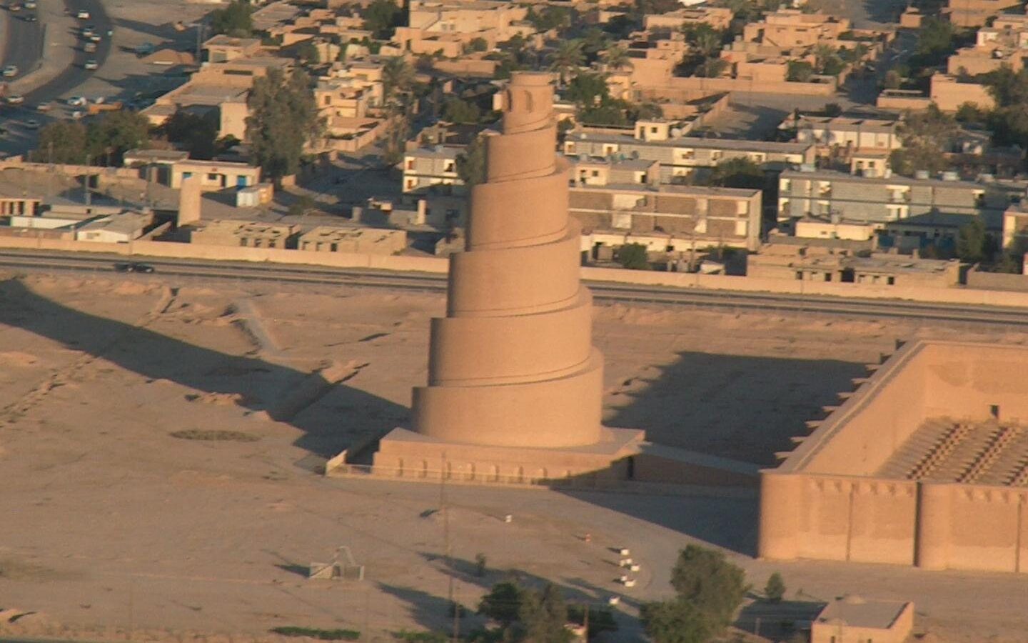 The spiral Malwiya minaret and the brick walls of the Great Mosque of Samarra, with the modern city behind