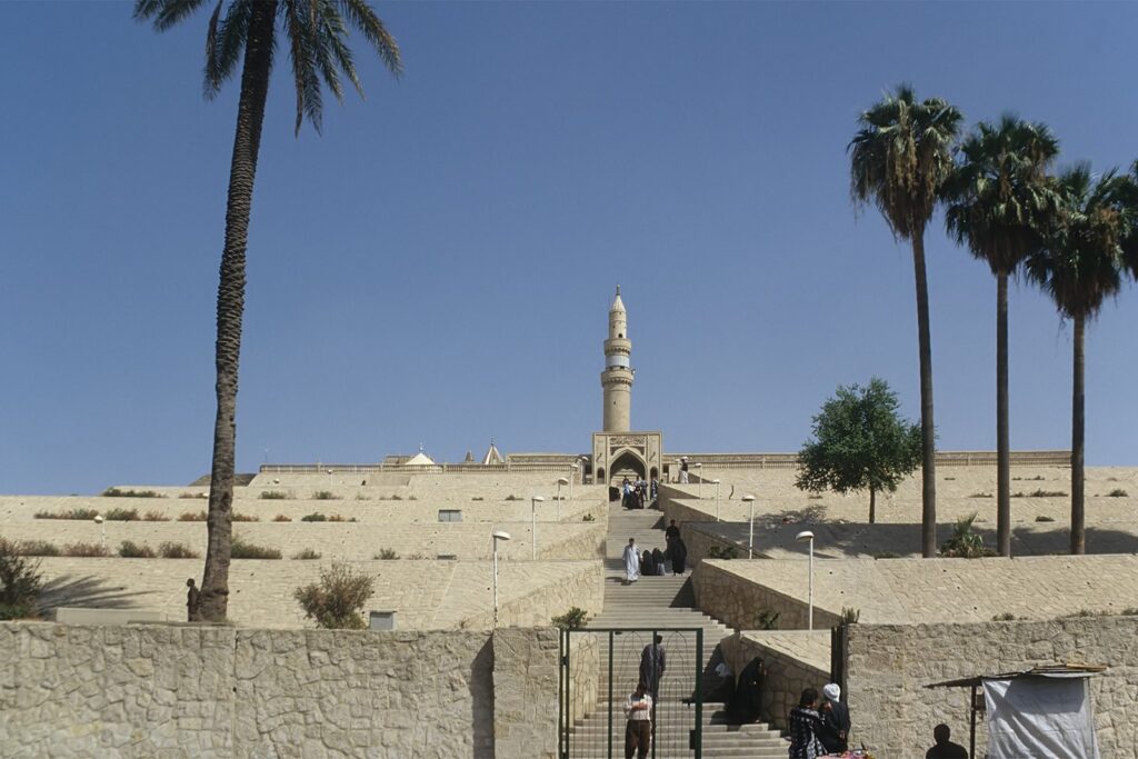The Mosque of the Prophet Yunus on its mound at Nineveh in 1999, with a tall minaret and palm trees