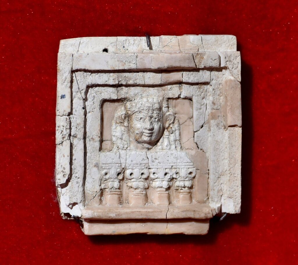 Carved ivory plaque from Nimrud showing a woman's face framed in a window above a balustrade