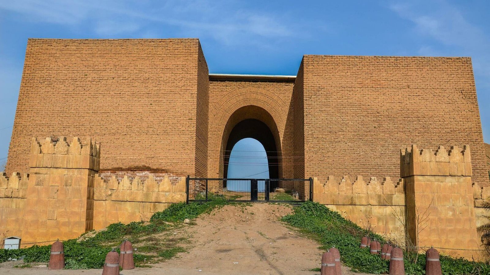 The reconstructed Mashki Gate of Nineveh, a brick gatehouse with crenellated walls on the edge of Mosul
