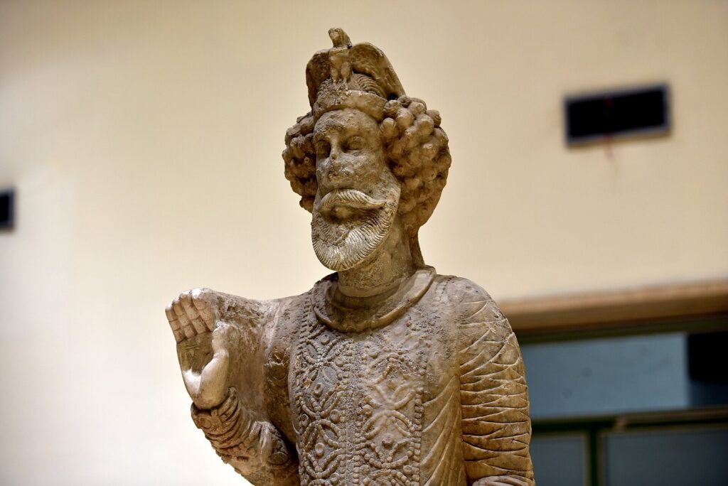 Limestone statue of King Sanatruq I of Hatra with curled hair, an eagle on his headdress and his right hand raised