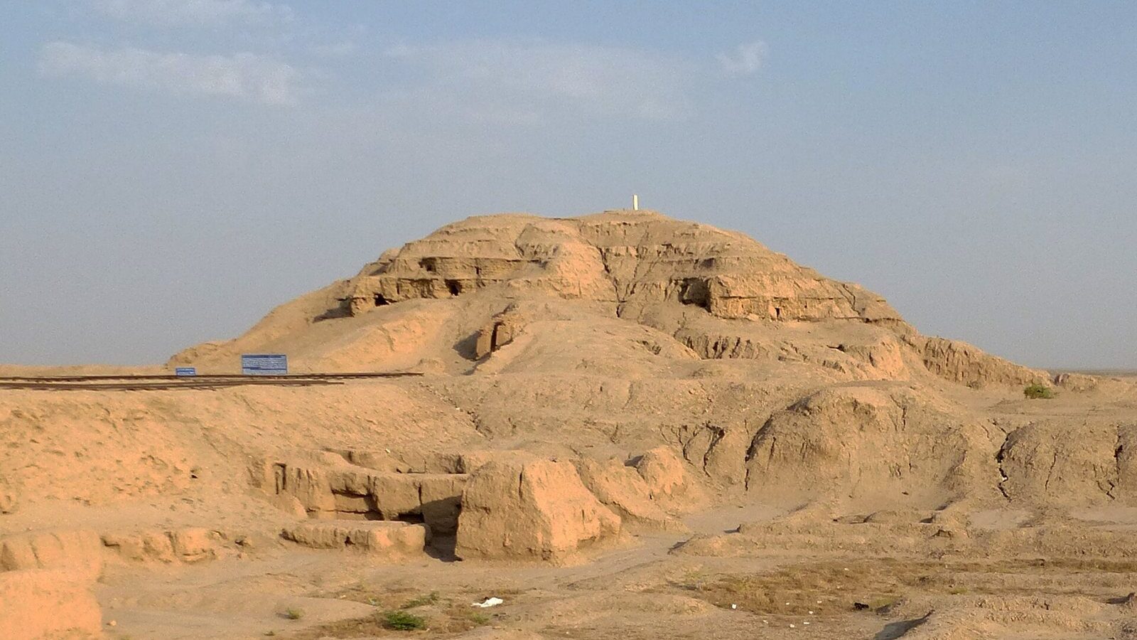 The eroded mud-brick Anu ziggurat at Uruk, which carried the White Temple, under a pale sky in southern Iraq